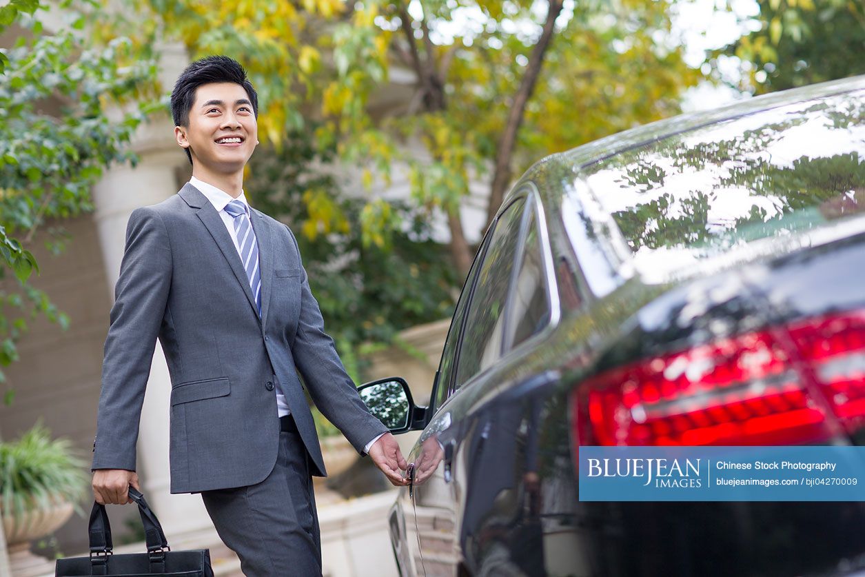 Young Chinese businessman opening car door