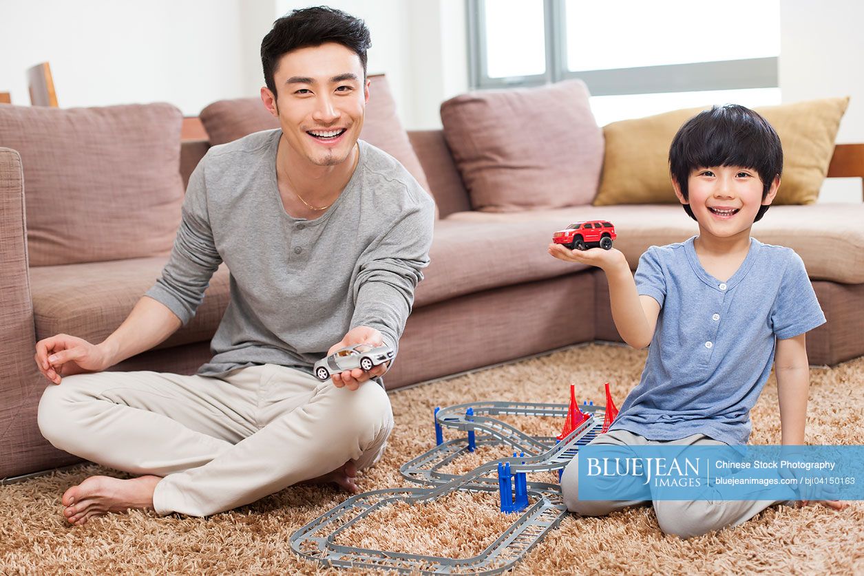 Chinese father and son playing toy car in living room