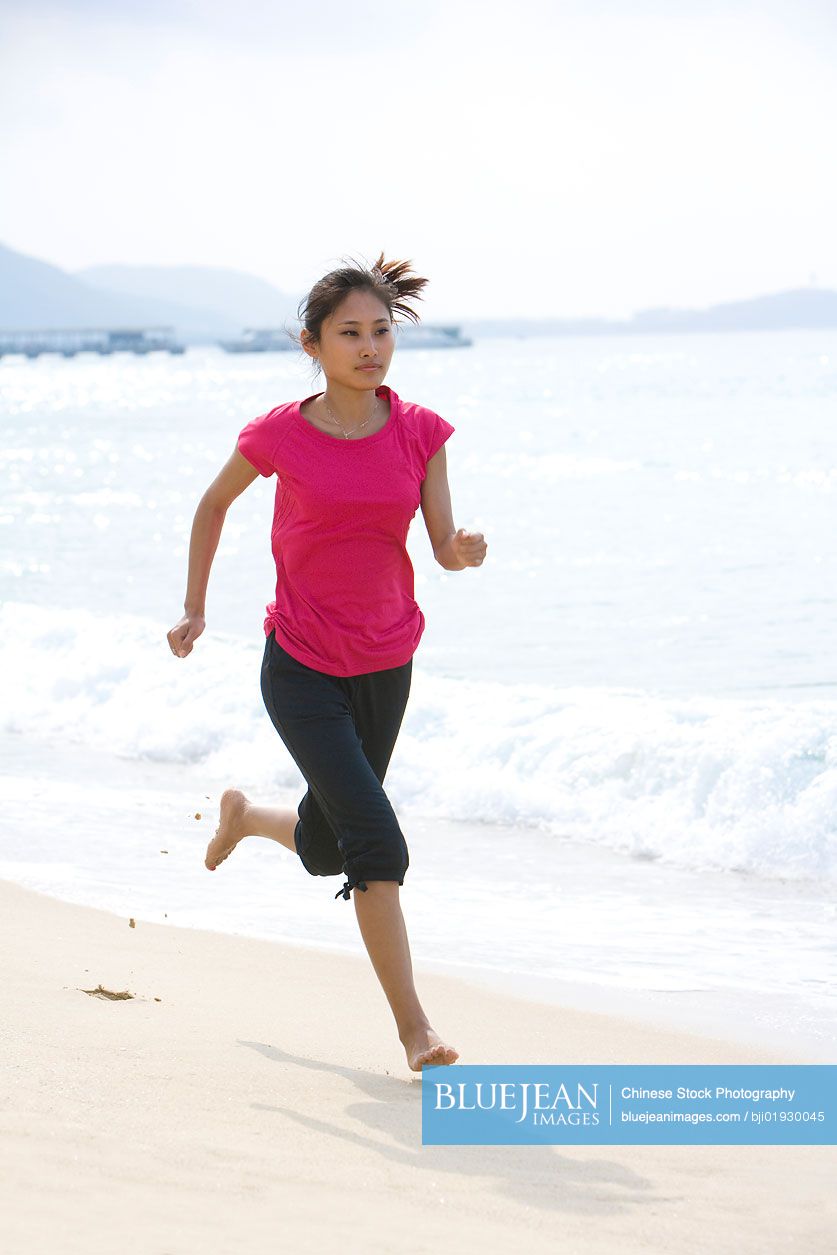 Young Chinese woman running on the beach