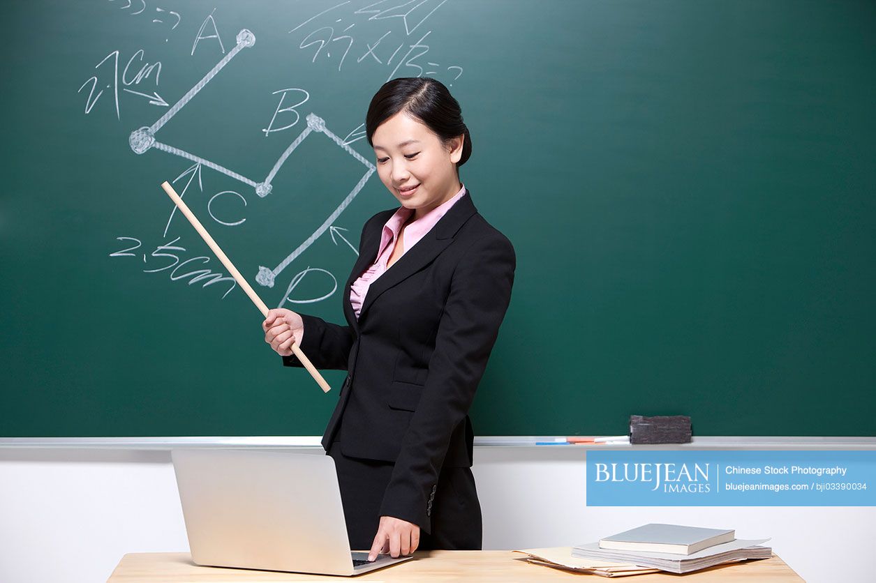 Female Chinese teacher using laptop in classroom