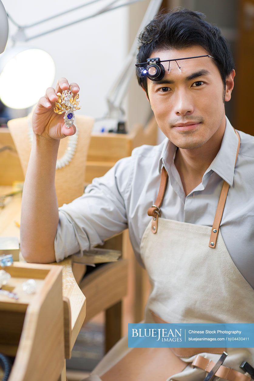 Chinese male jeweler holding a broochHighres stock photo for download