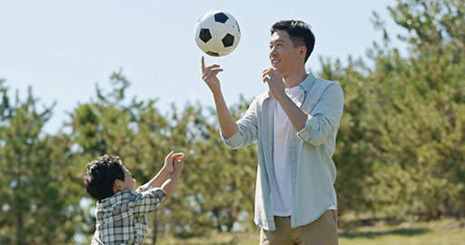 Happy Chinese father and son playing football in park,4K