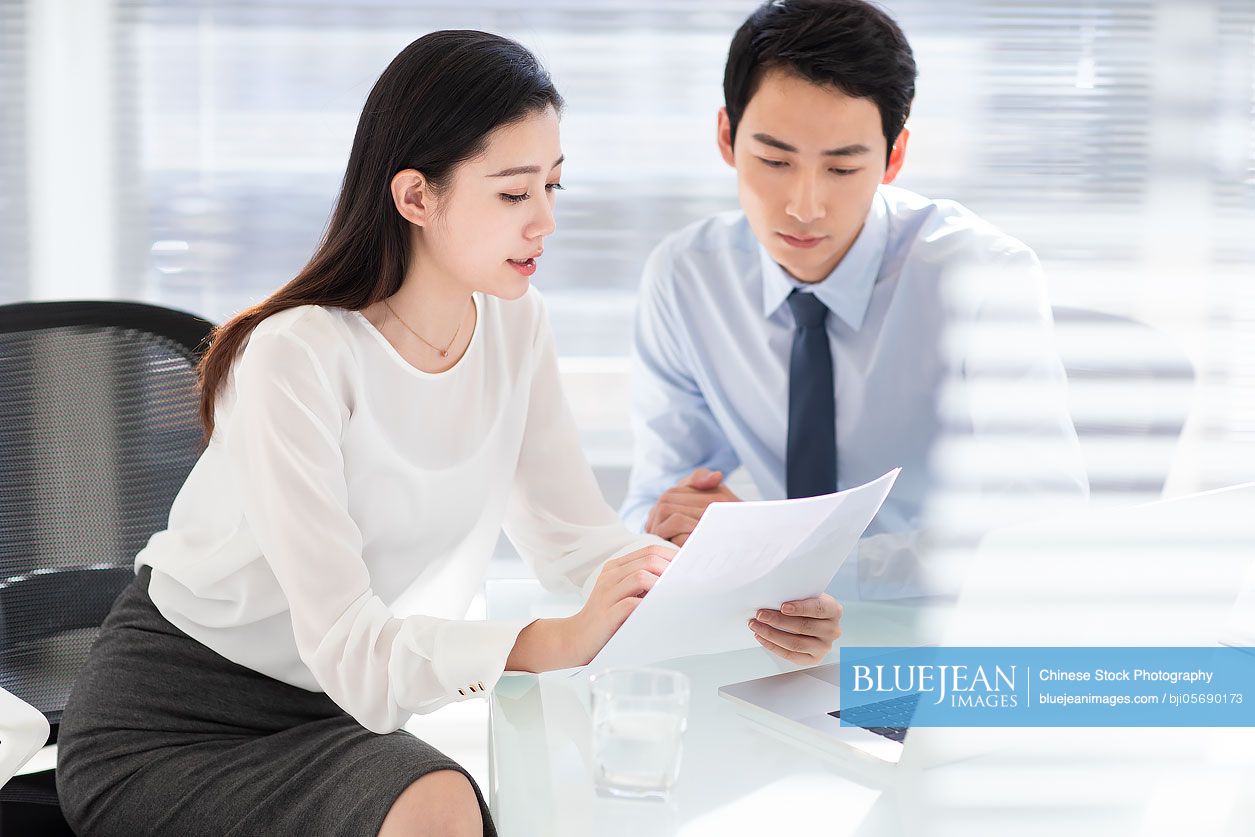 Young Chinese business people using laptop in office