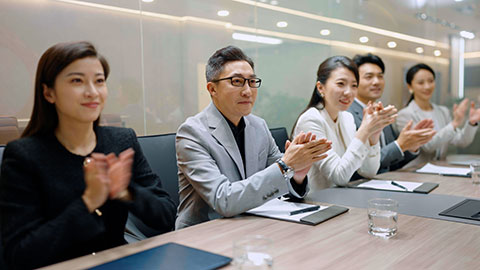 Cheerful Chinese business people applauding in meeting room