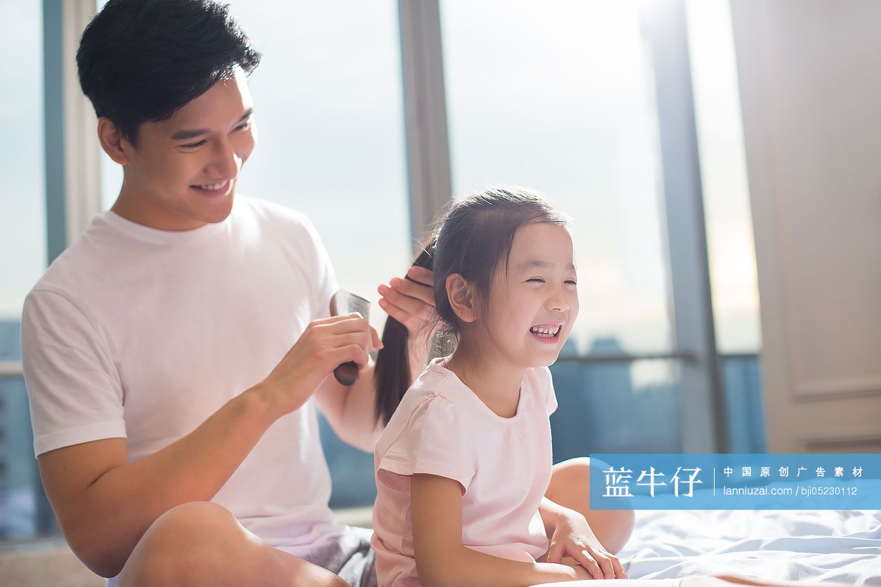 年轻爸爸在床上给女儿梳头