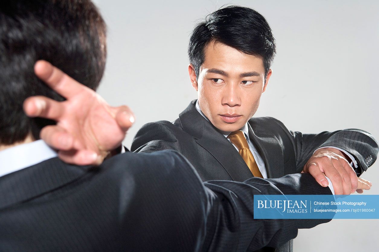 Two Chinese businessmen fighting on grey background