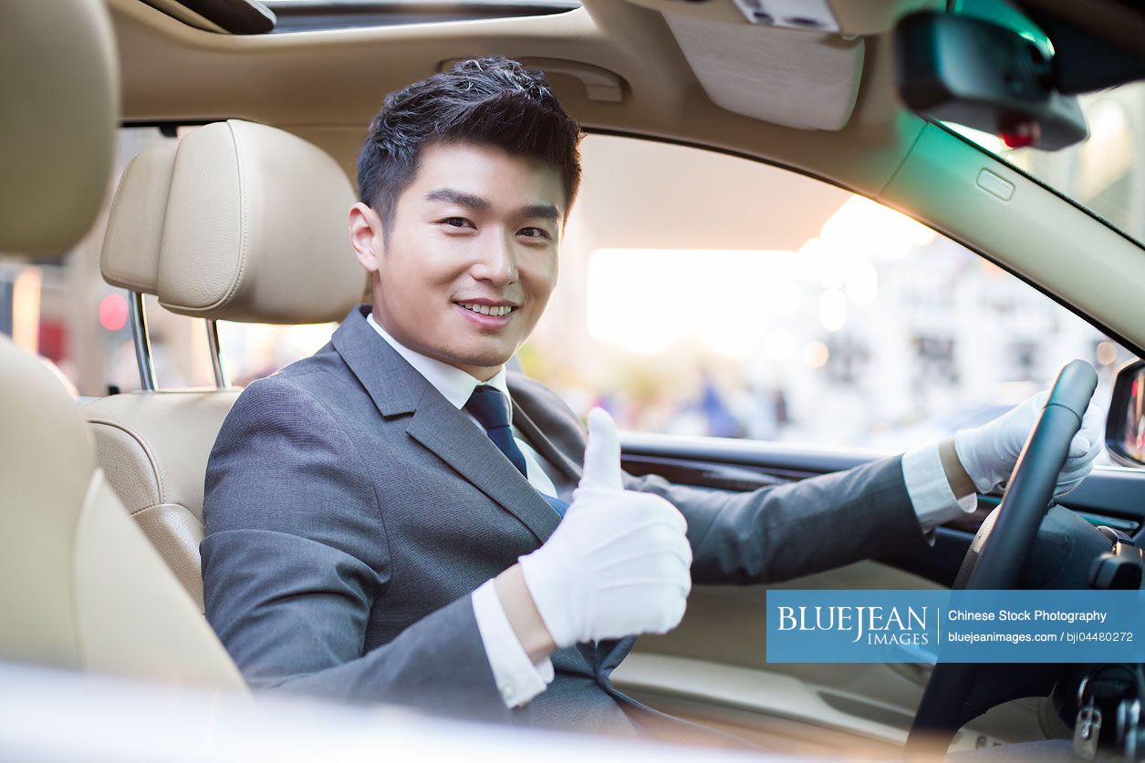 Chinese chauffeur doing thumbs up inside car