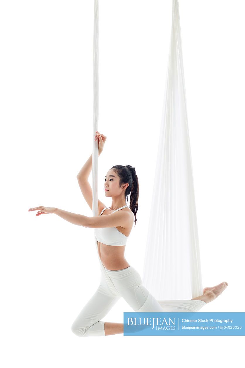 Young Chinese woman practicing aerial yoga