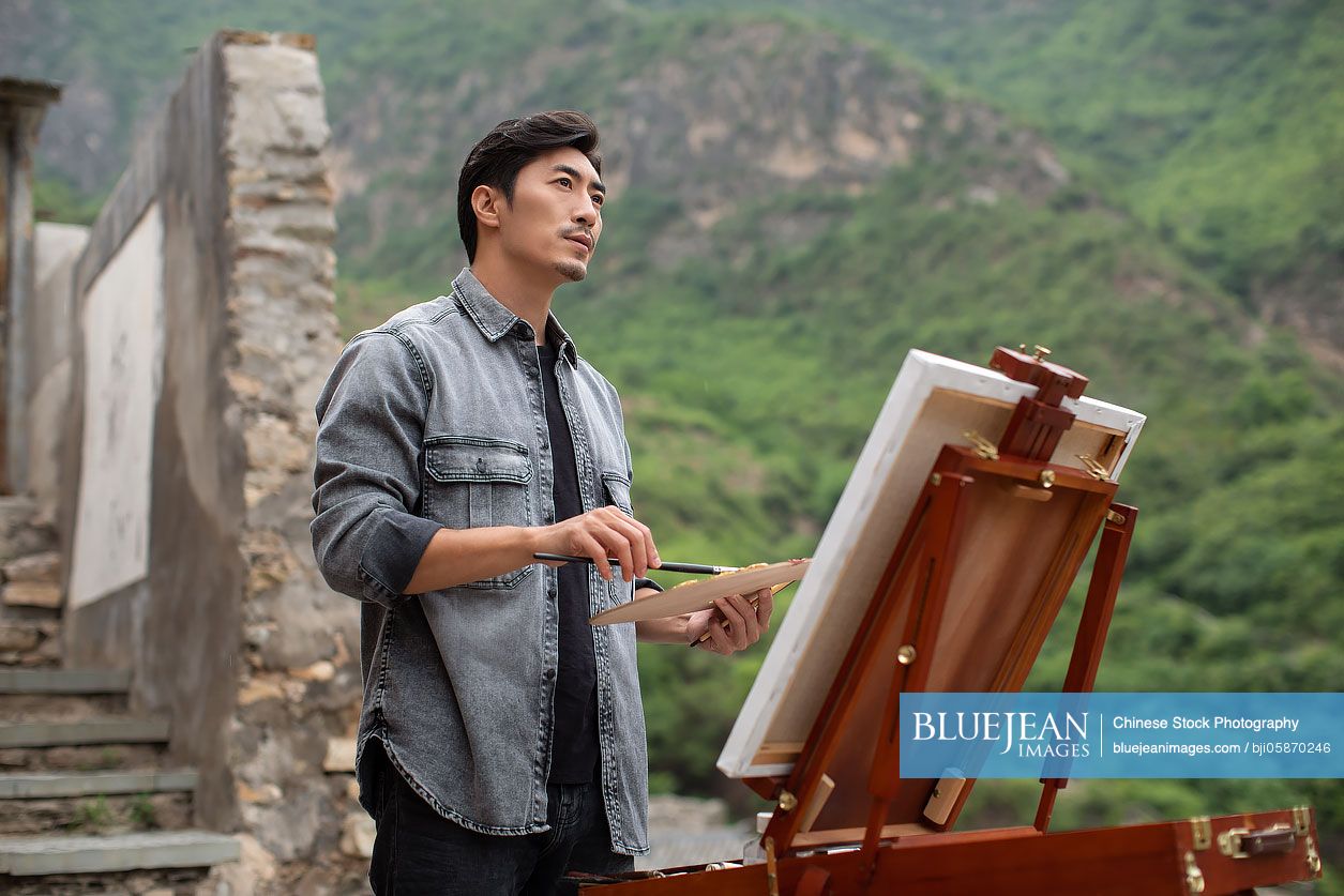Young Chinese artist painting outdoors