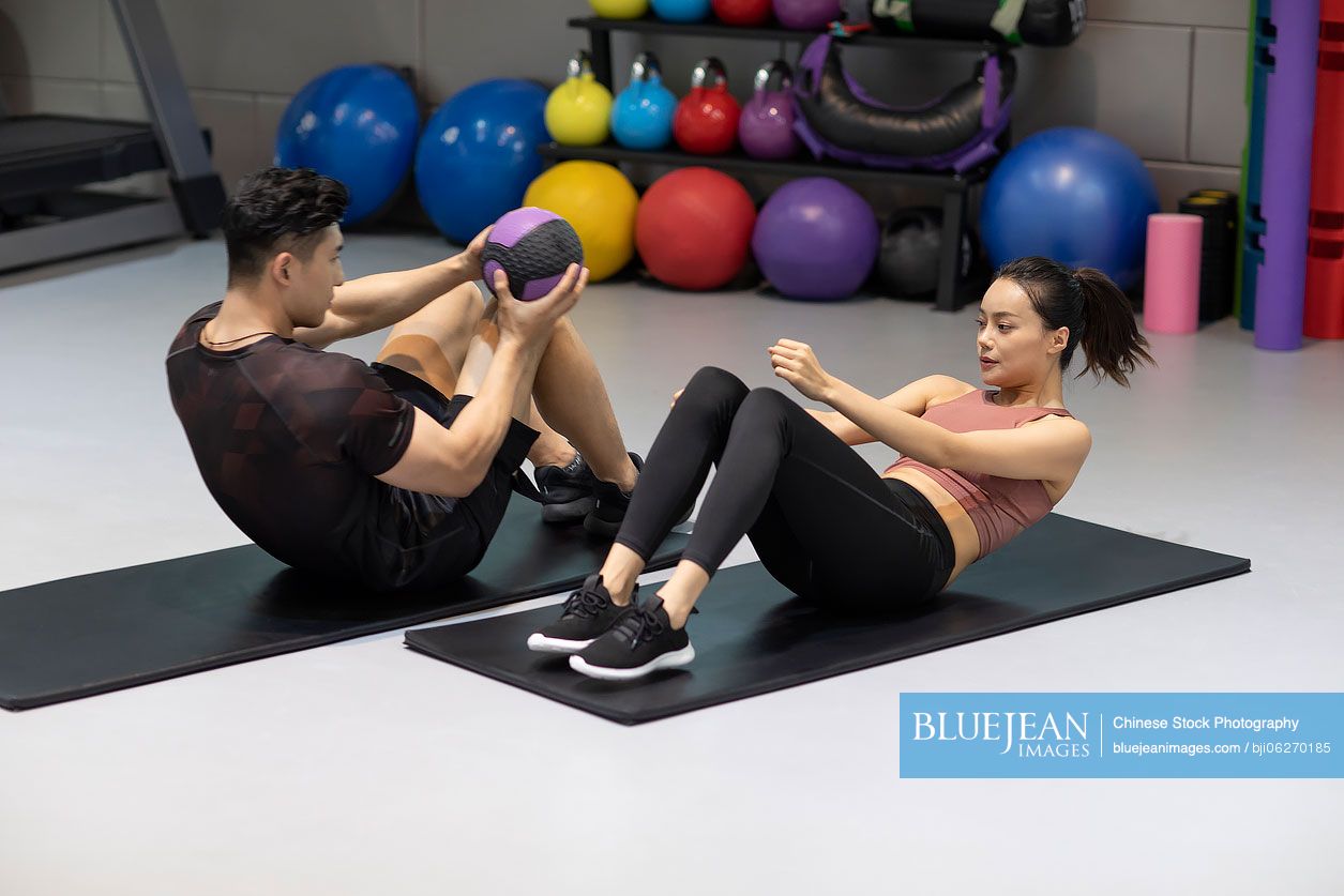 Young Chinese woman working out with personal trainer at gym-High