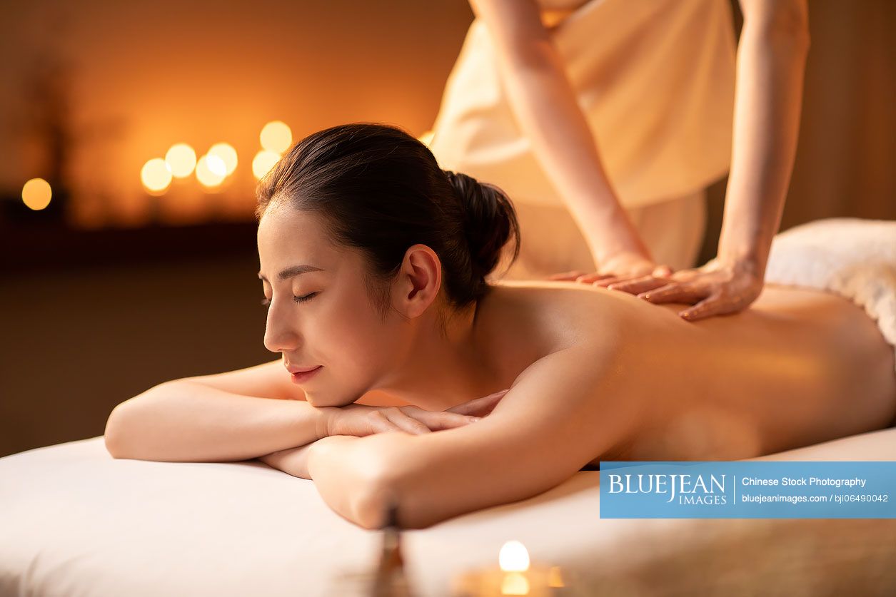 Young Chinese woman receiving back massage at spa center