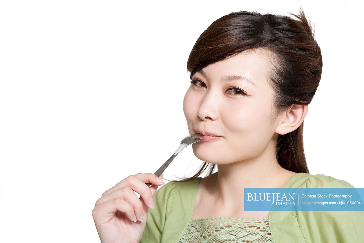 Portrait of young Chinese woman eating from spoon