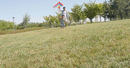 Happy Chinese father and son running with kite on meadow,4K