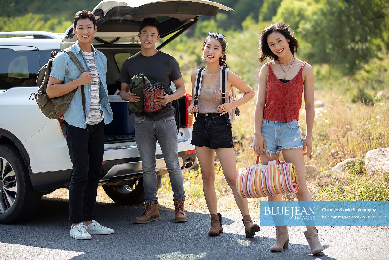 Happy young Chinese friends camping outdoors
