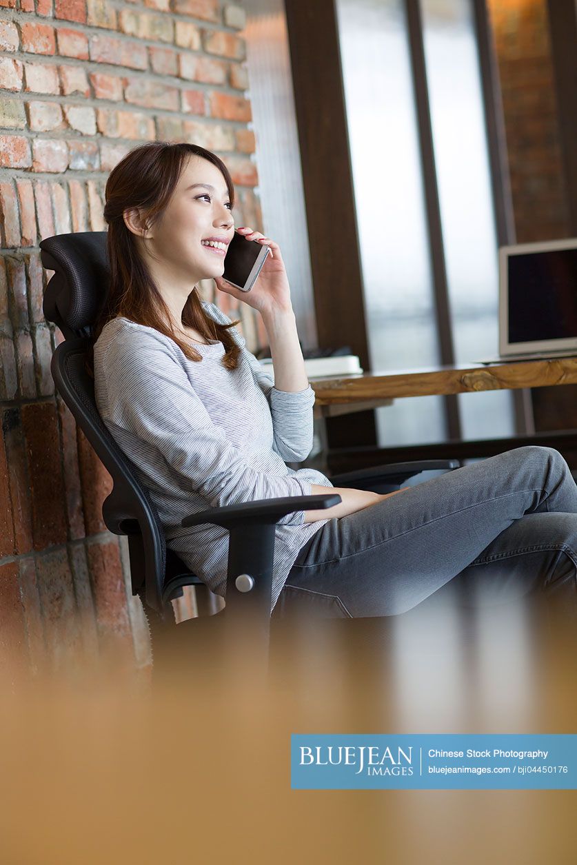 Young Chinese woman talking on the phone in office