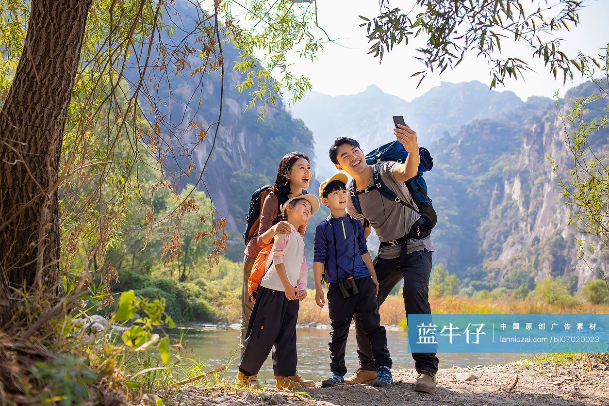 快乐的年轻家庭在户外用手机自拍