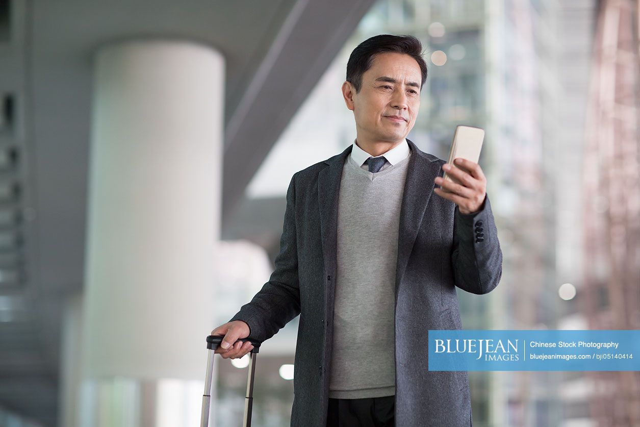 Chinese businessman using smart phone in airport