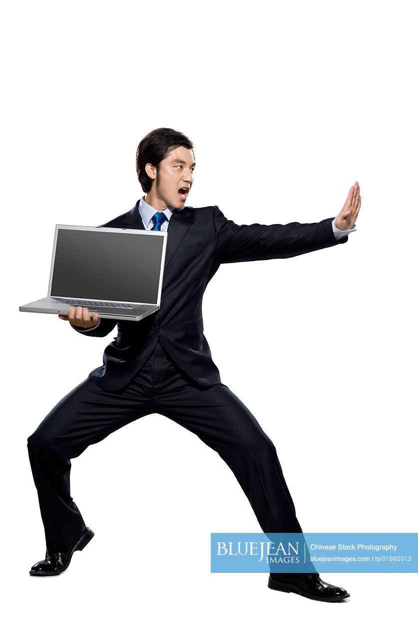 Chinese businessman in fighting stance holding laptop