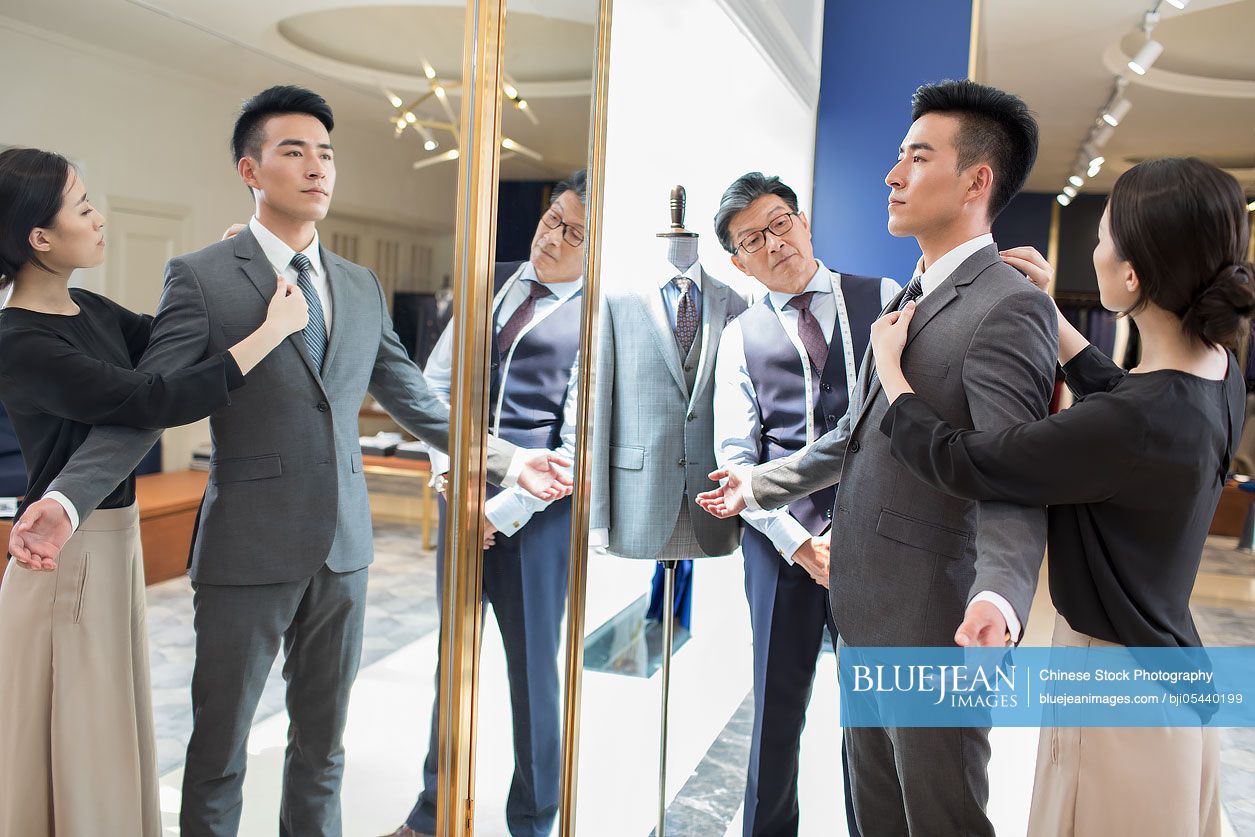 Chinese fashion designers examining suit on customer