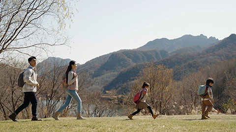 Happy young Chinese family hiking outdoors