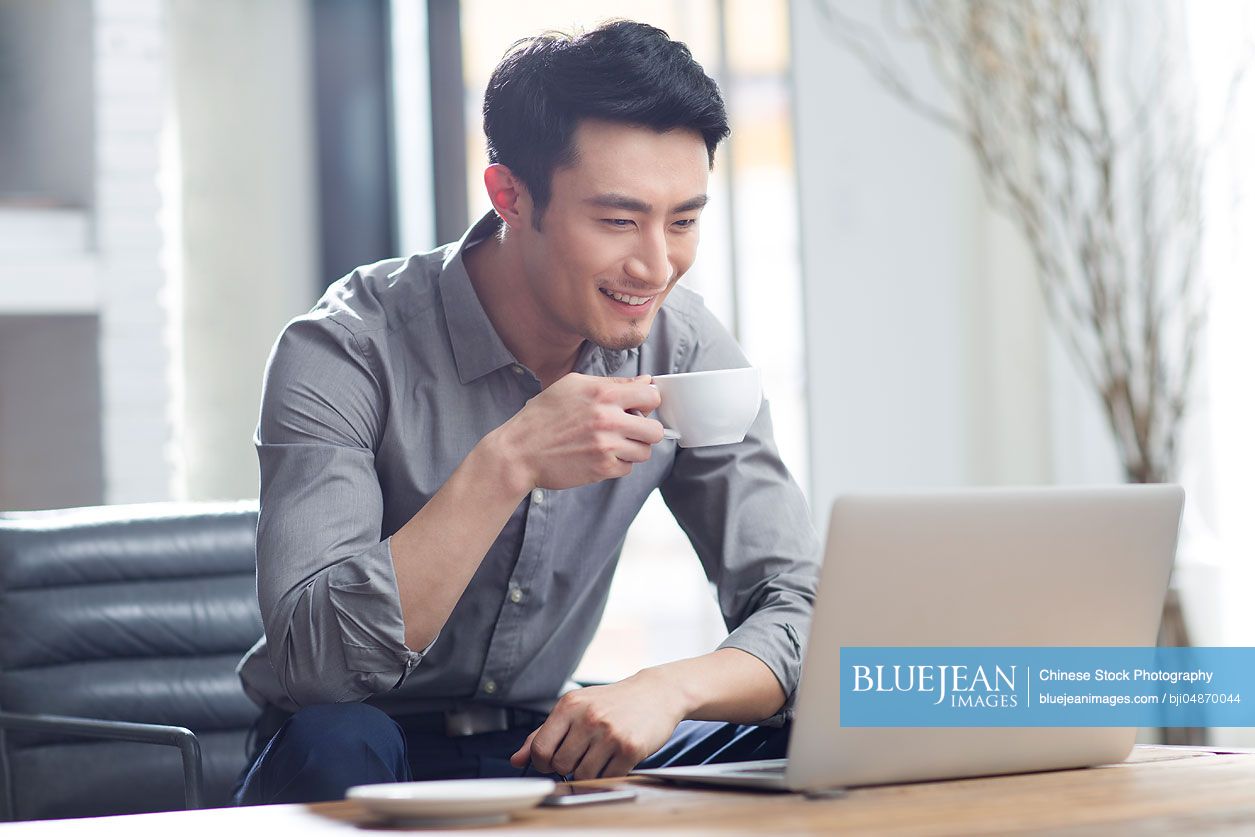 Young Chinese man working with laptop in office