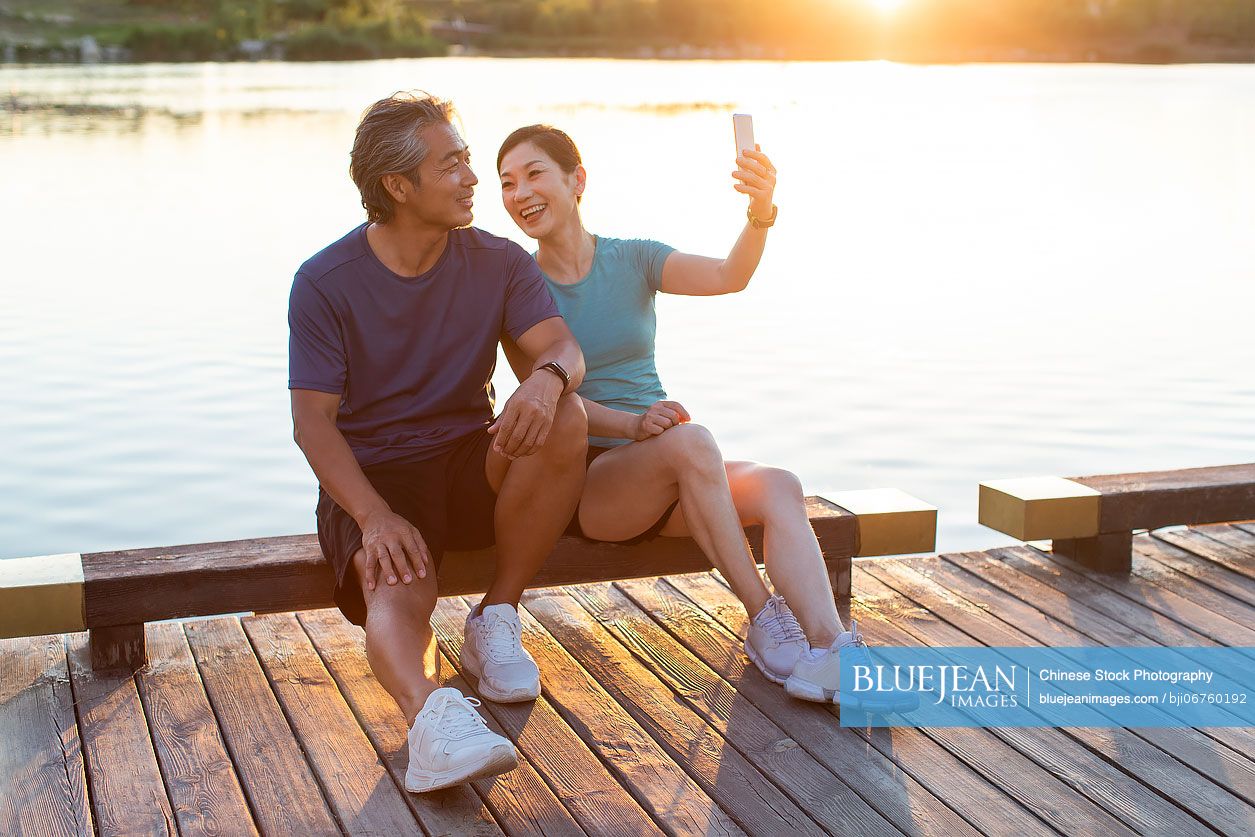 Happy mature Chinese couple taking selfie in park