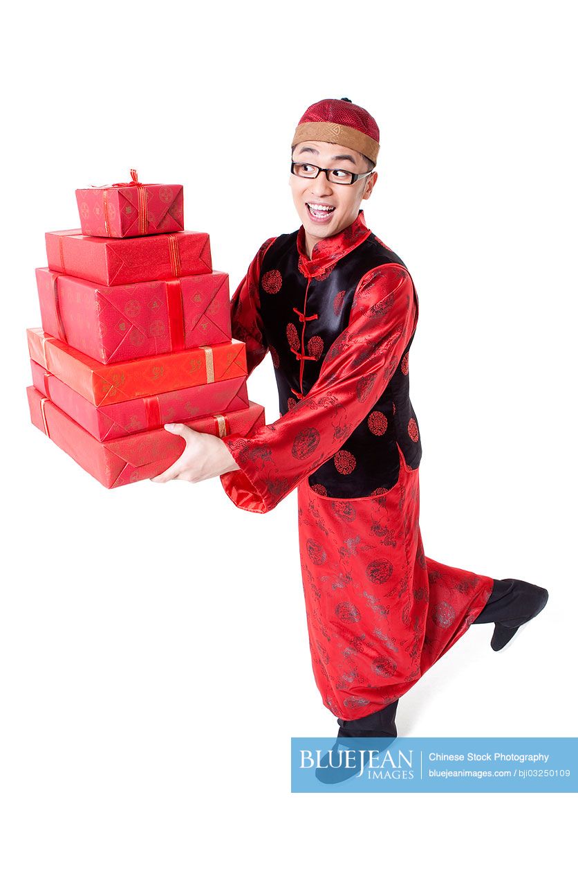 Happy young Chinese man in Tang suit holding gift boxes