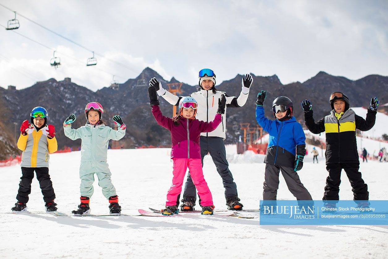 Chinese children learning how to snowboard with their coach