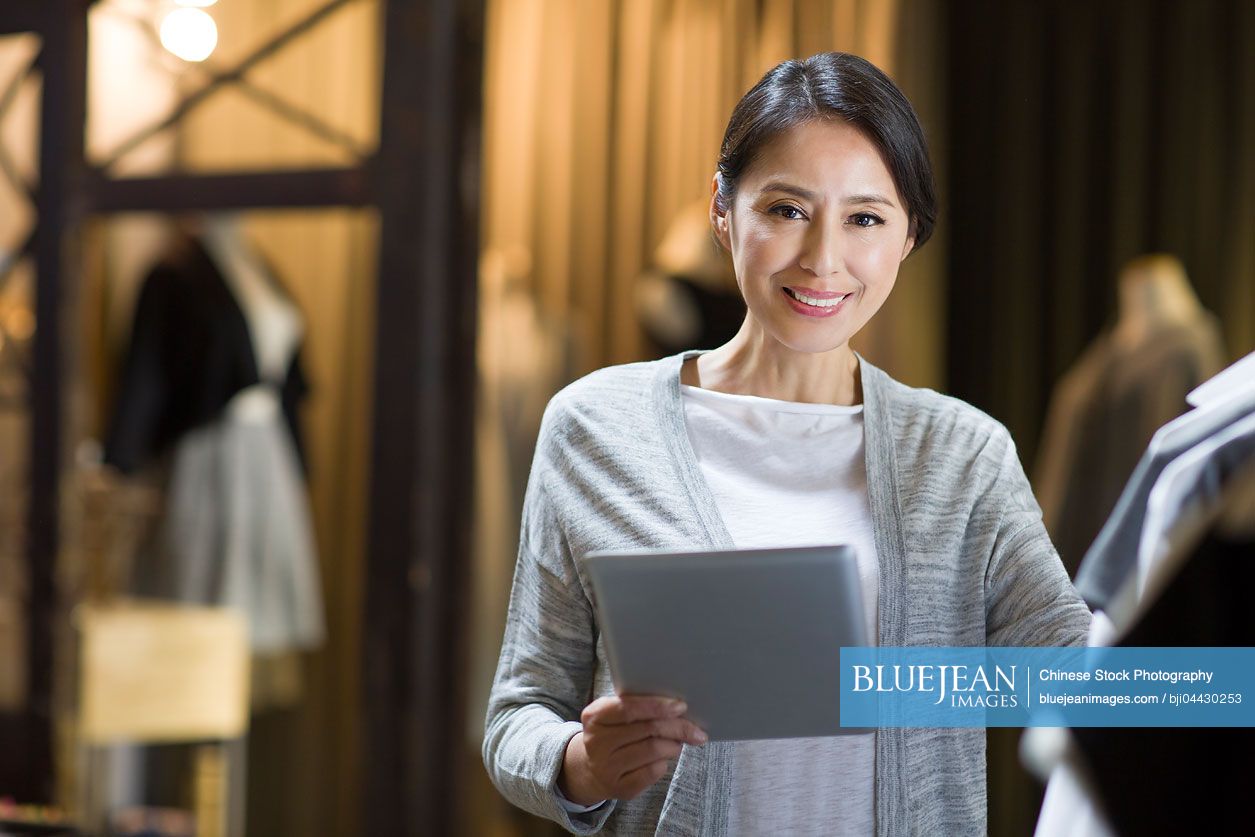 Chinese clothing store owner with digital tablet