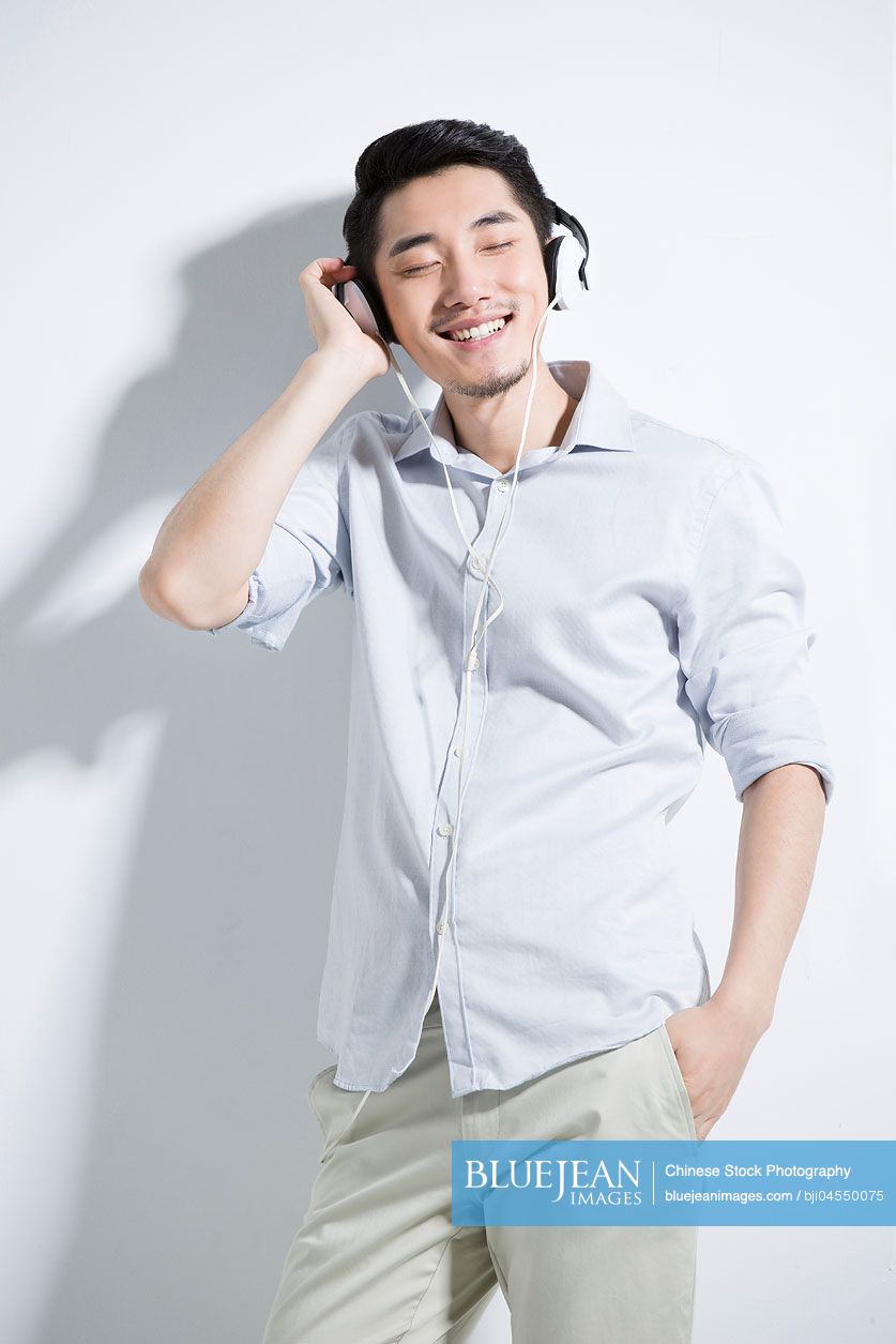 Happy young Chinese man listening to music