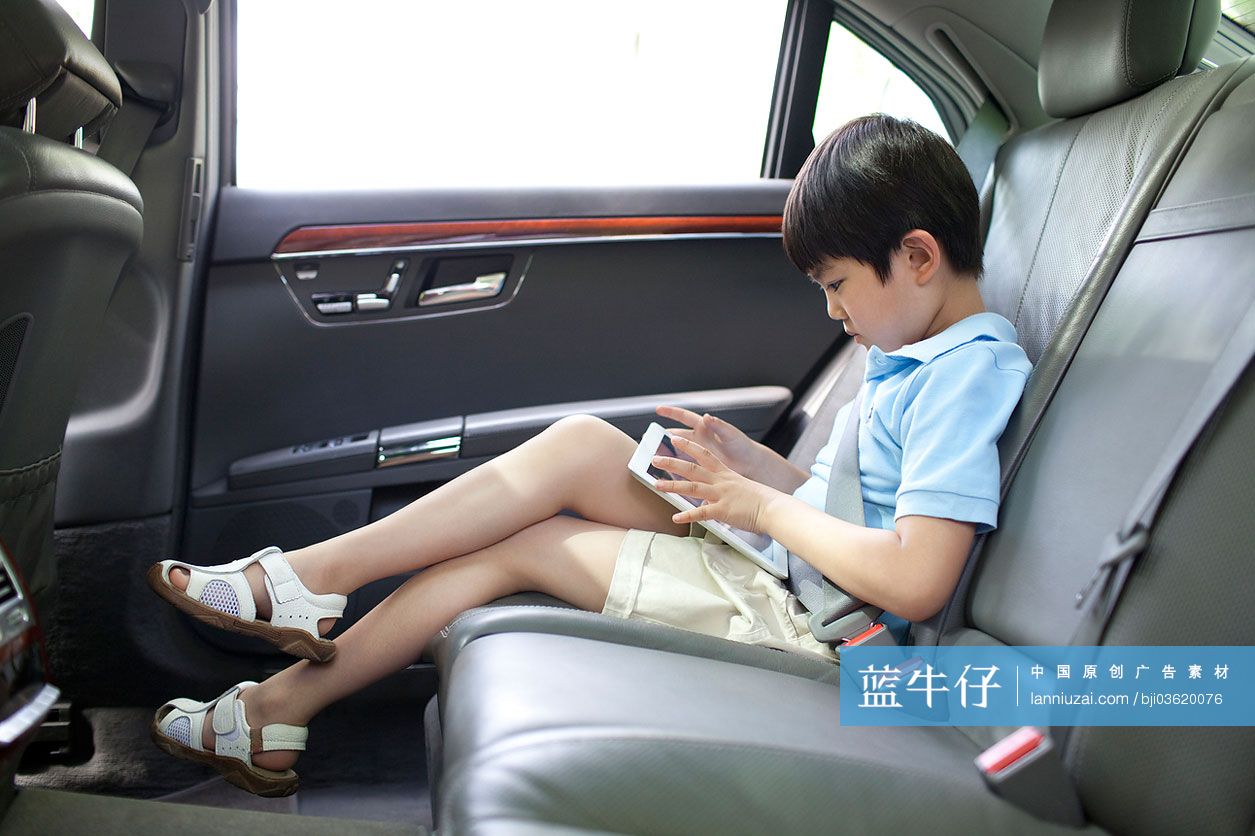 小男孩坐在车上玩平板电脑