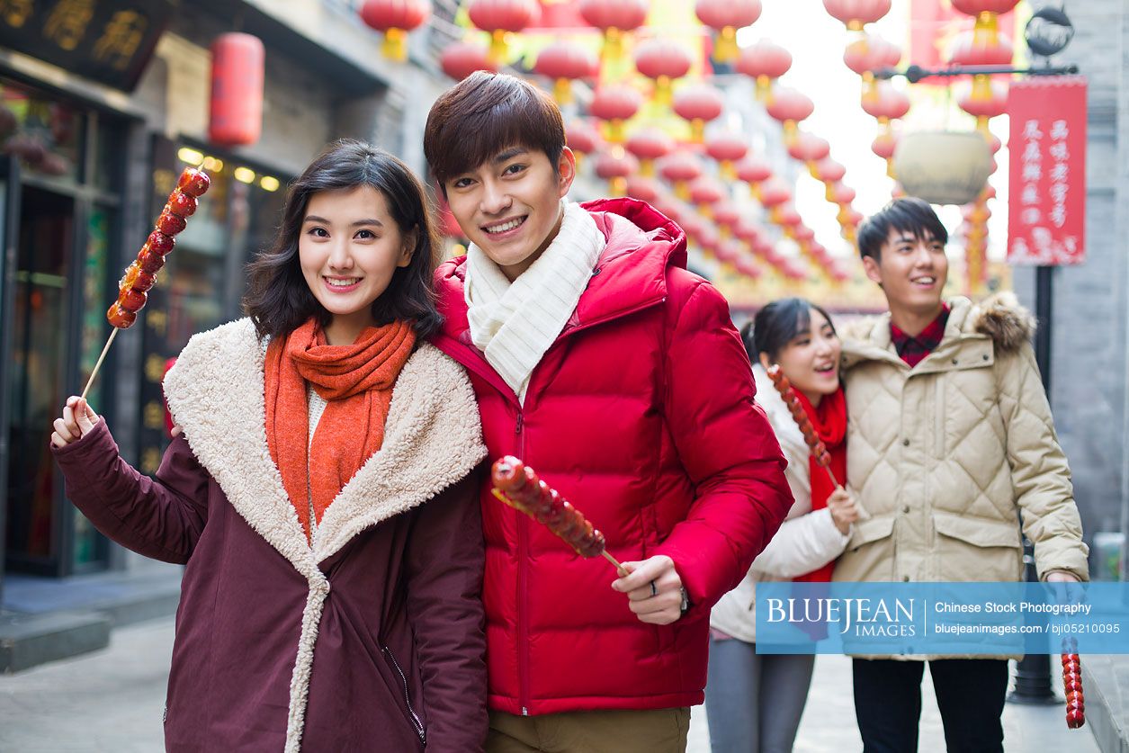 Young Chinese friends with candied haw berries celebrating Chinese New Year