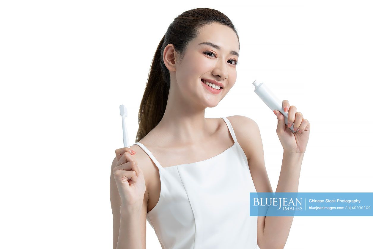 Beautiful young Chinese woman brushing teeth