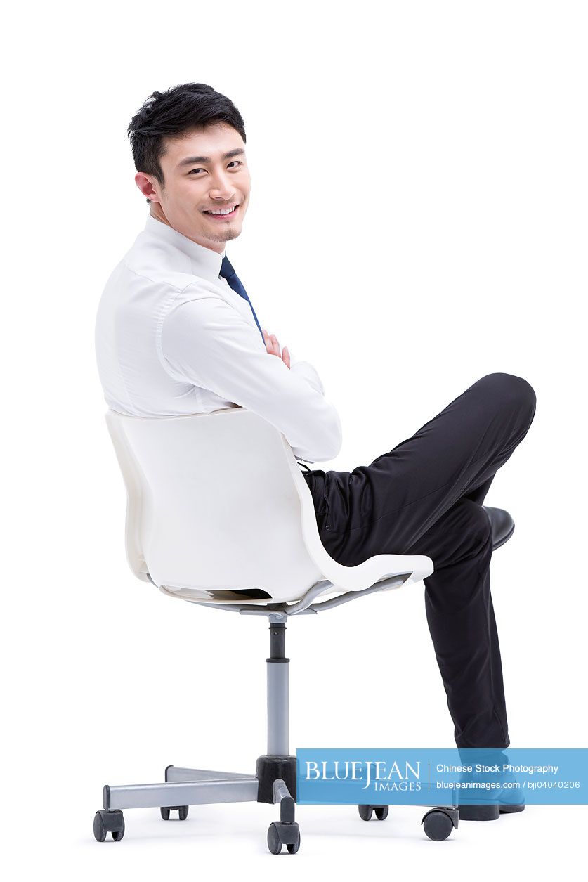 Confident young Chinese businessman sitting on chair