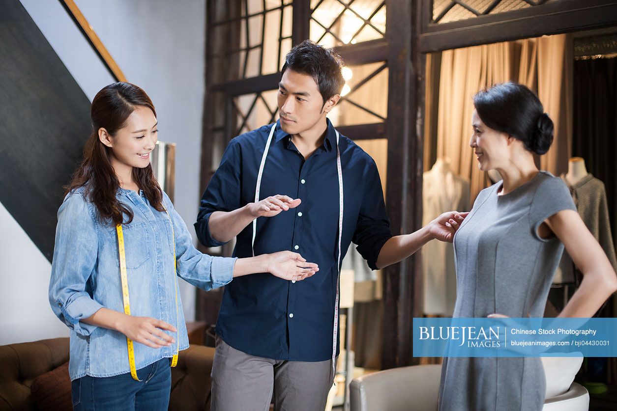 Chinese fashion designers adjusting customer's dress