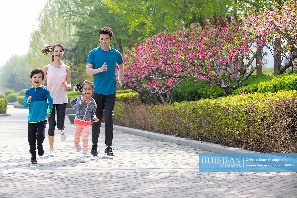 Happy young Chinese family running in park