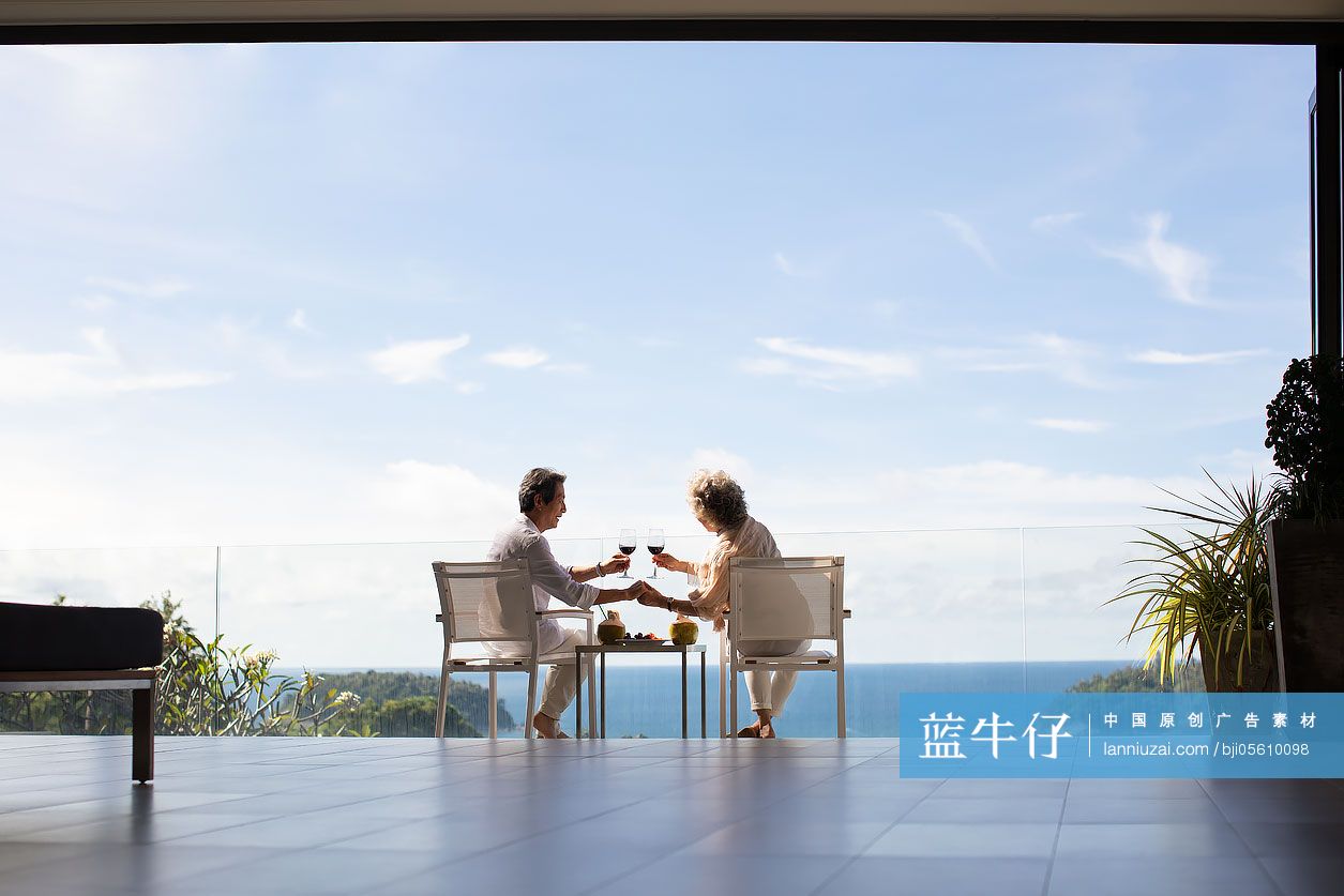 快乐的老年夫妇在阳台喝红酒