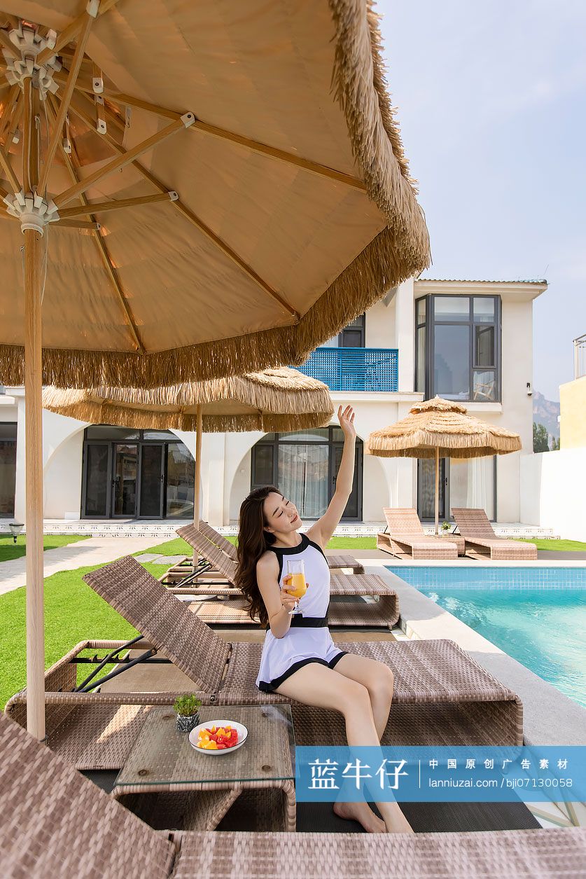 年轻女子在躺椅上喝果汁