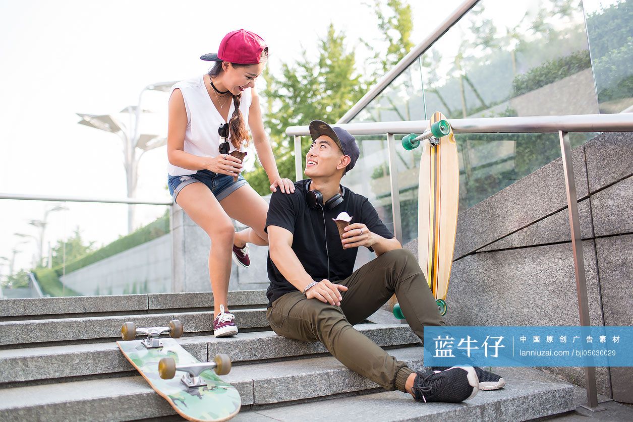 带着滑板的快乐年轻情侣在楼梯上吃冰淇淋