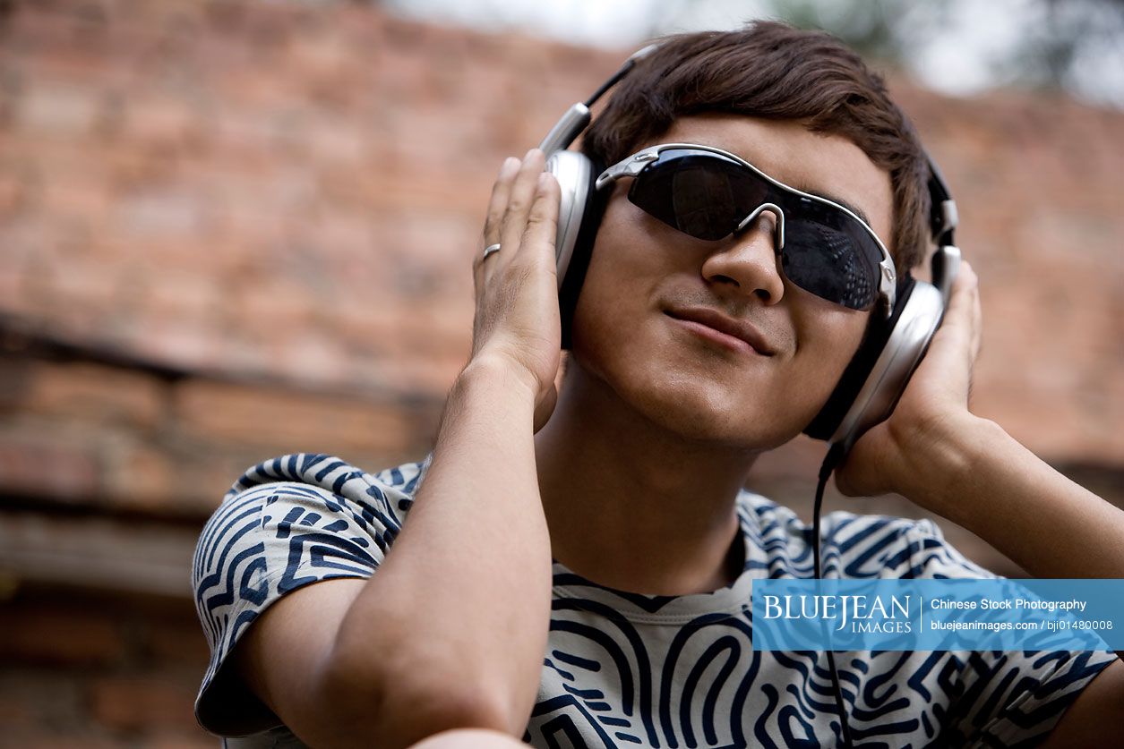 Young Chinese man listening to music on headphones