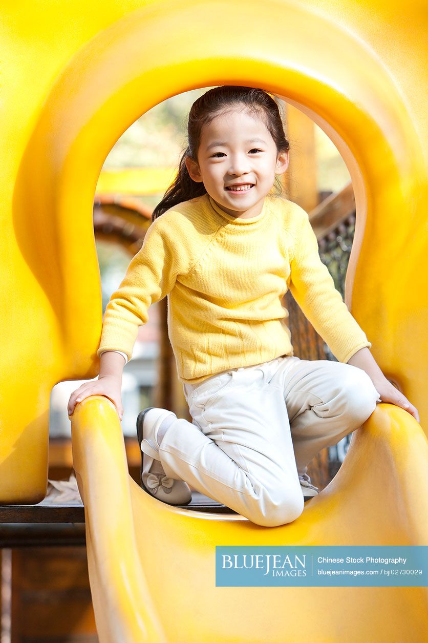 Chinese girl playing on playground slide