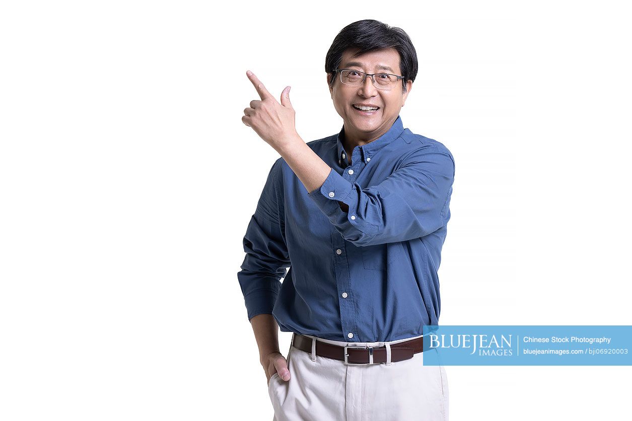 Studio shot of cheerful senior Chinese man pointing