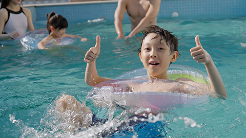 Happy family swimming and playing in the sparkling pool