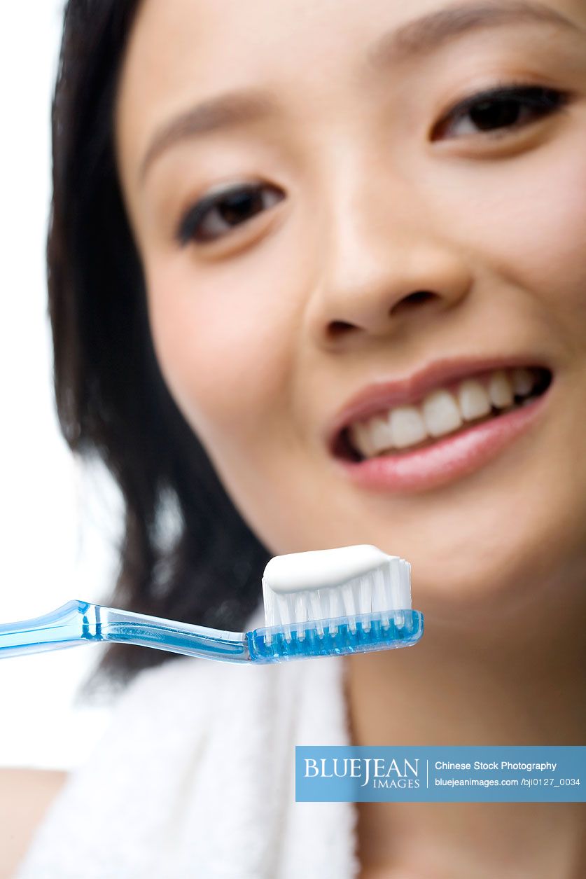 Chinese young woman smiling and holding up a toothbrush