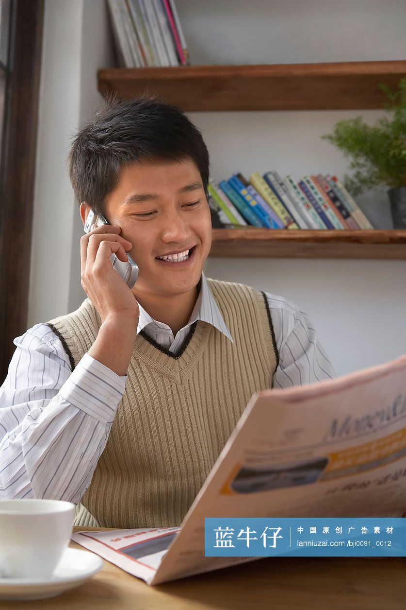 在书吧打电话看报纸的年轻人