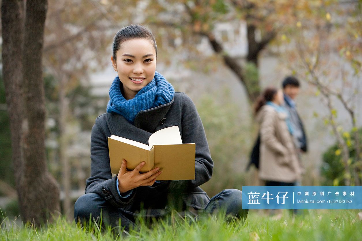 青年女子坐在草地上看书
