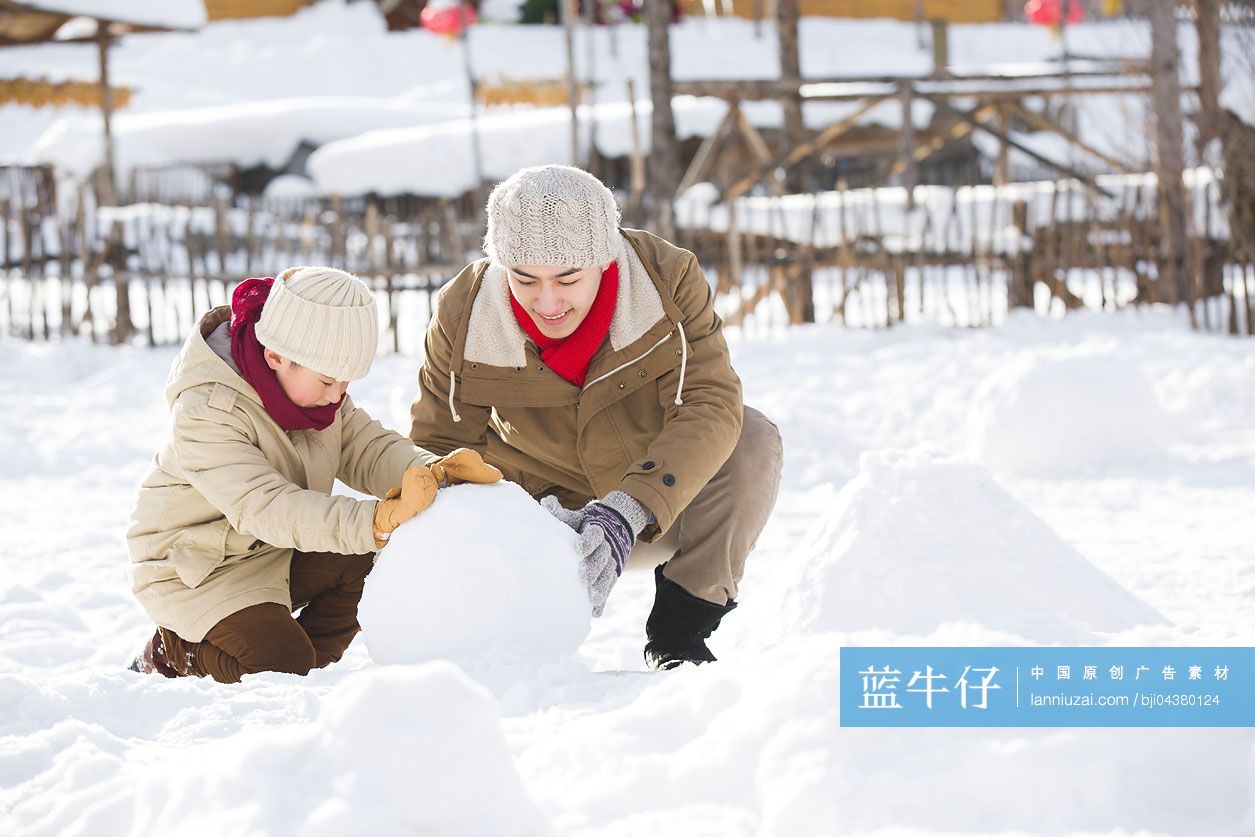 快乐的父子俩在雪地上滚雪球