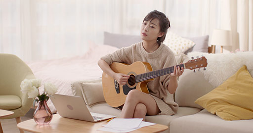 年轻女士在家弹吉他谱曲