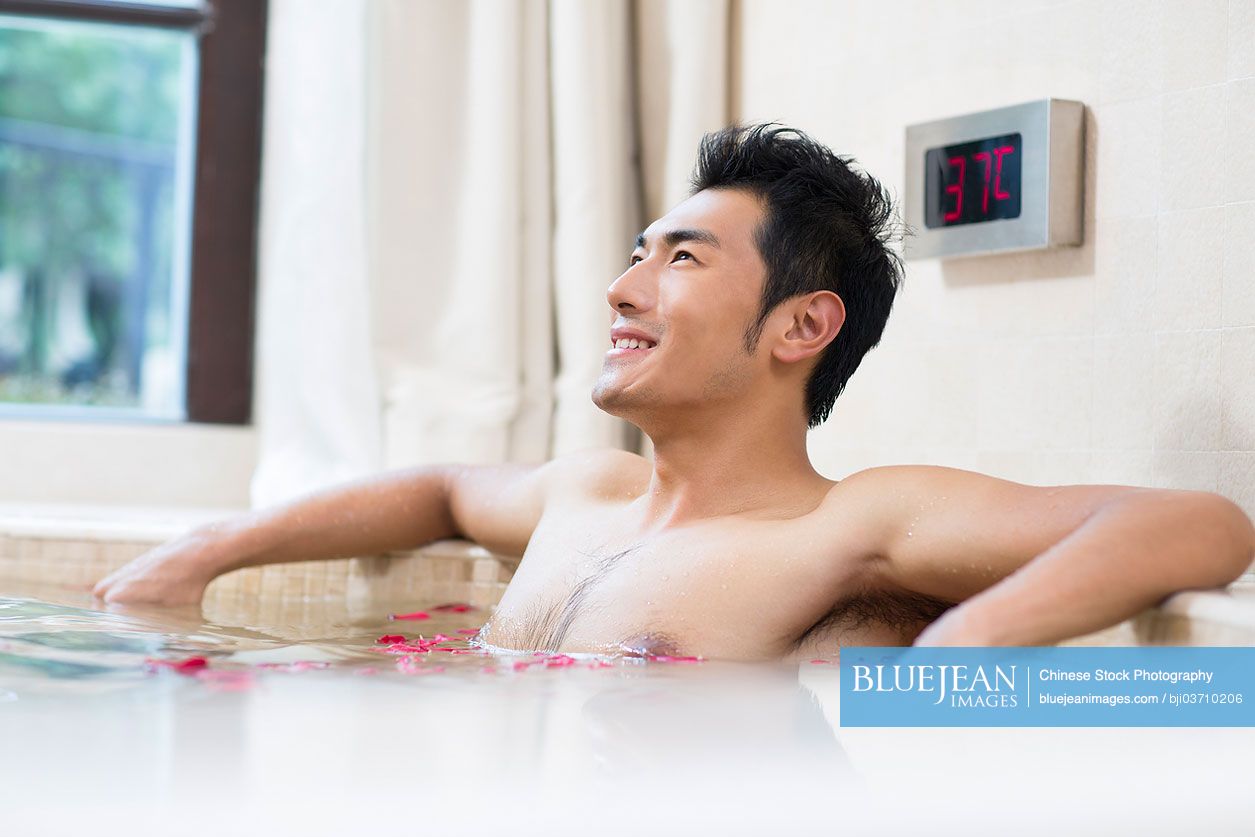 Young Chinese man relaxing in a nice hot bath