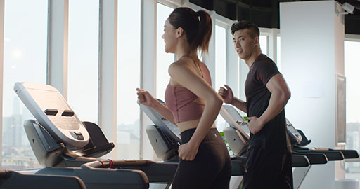 Young Chinese couple running on treadmill at gym,4K